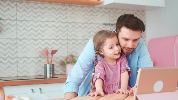Smiling father and daughter looking cartoon on laptop in the kitchen. Happy family leisure alt