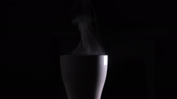 Steam from a white cup with boiling water. A trickle of steam rises from a cup of hot coffee. 