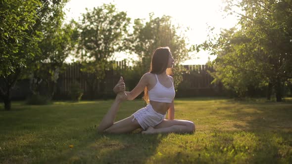 Young Woman Practicing Yoga at Sunrise in the Garden