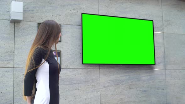 Young Smiling Business Woman Giving Presentation on Big Green Screen alt