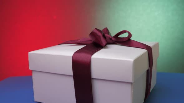 Christmas Box with Ribbon Under Colourful Flashing Lights alt