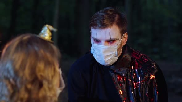 Portrait of Young Man in Vampire Costume with Face Paint in Coronavirus Face Mask Celebrating alt