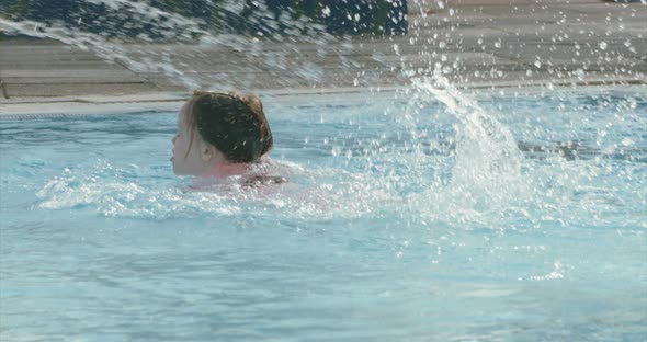 Slow motion shot of a little girl playing in a swimming pool during summer alt