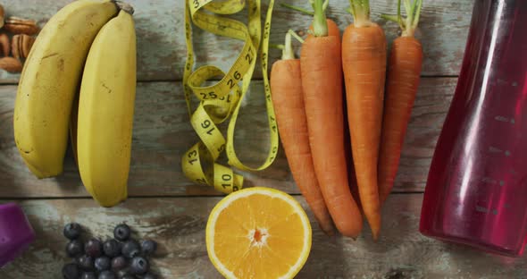 Video of fresh fruit, measuring tape, water bottle and dumbbells on wooden boards alt