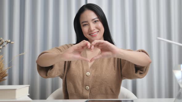 A woman shows a heart sign above her chest, love and peace to you, showing kindness.