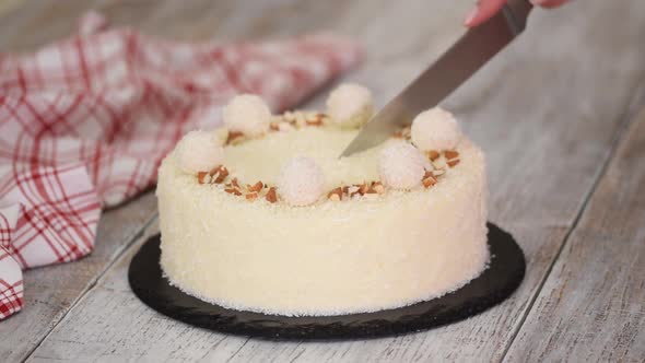 Cutting a Delicious Coconut Mousse Cake Decorated with Candy and Almond