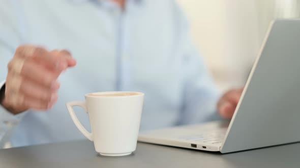 African Man Working on Laptop and Drinking Coffee Close Up alt