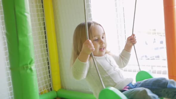 Child Swings on Swing Children's Play Center Little Girl