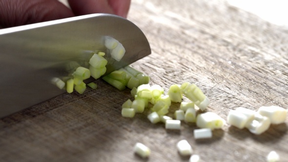 Chopping green onion by knife Close Up on Cutting Board