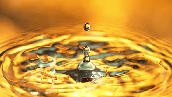 Super Slow Motion Detail Shot of Water Drop on Golden Luxury Background at 1000 Fps alt