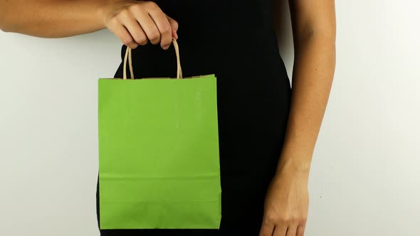 A woman holds a green shopping bag in honor of Black Friday and Cyber Monday.