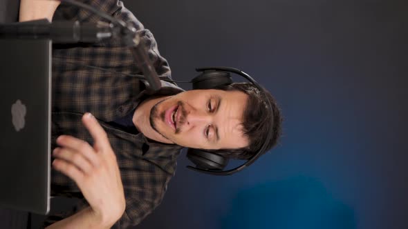 Cheerful guy inn headphones using laptop while recording vlog in studio alt