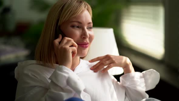 A Smiling Blonde Woman Making a Friendly Phone Call Can Talk To a Business Contact or Friend alt