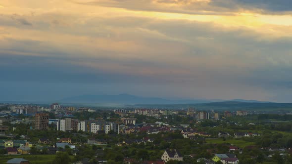 Time lapse footage of fast moving evening clouds on yellow sky over rural city area with distant alt