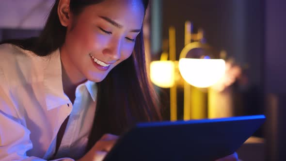 Young Asian beautiful woman enjoy using smartphone in bedroom at night time. alt