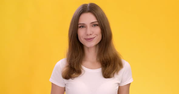 Studio Portrait of Young Cute Caucasian Woman Smiling Over Orange Background alt
