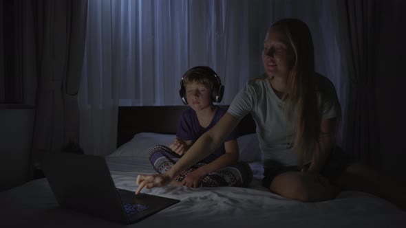 A Woman at Night Turns on a Meditation Relaxation Application on Her Computer for Her Son to Relax alt