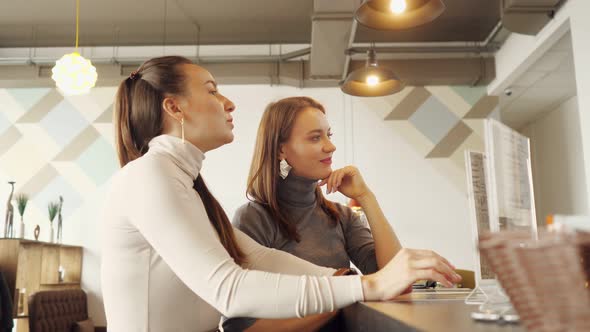 Two Women Discuss the Menu and Choose Food in a Cafe Standing at the Bar Counter. alt