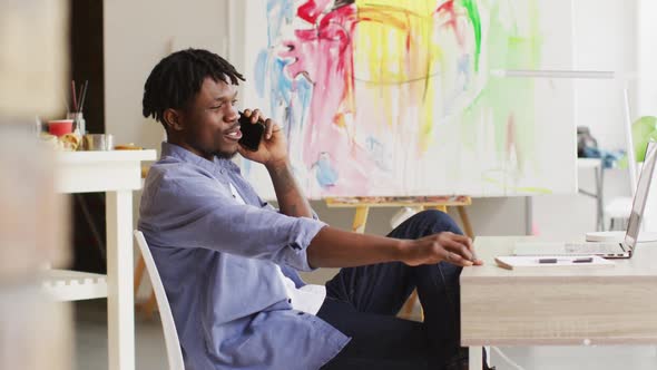 African american male artist talking on smartphone at art studio alt