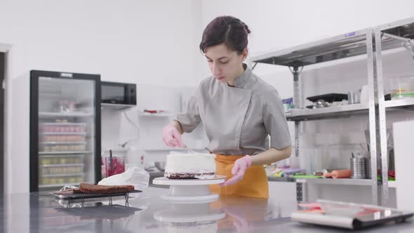 A Bright Pastry Chef Girl is Engaged in the Preparation of a Cake