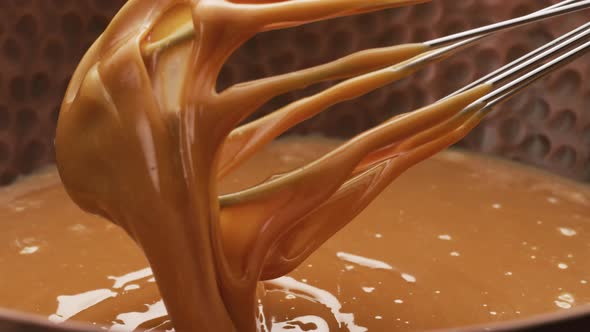 Melted caramel dripping from whisk, closeup food shot. 