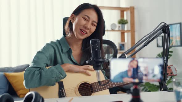 Asia girl influencer play guitar music use microphone record with smartphone for online.