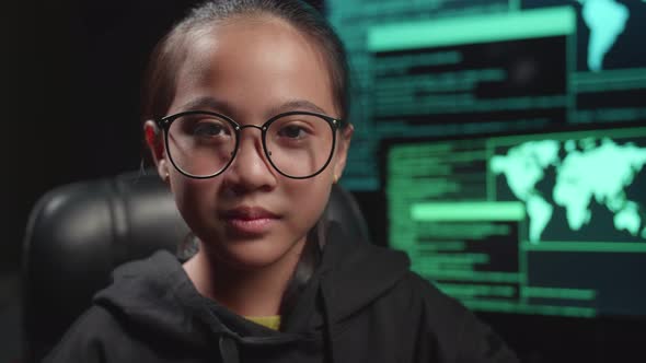 Asian Young Girl Hacker Takes Off Her Hood And Pose With Multiple Computer Screens alt