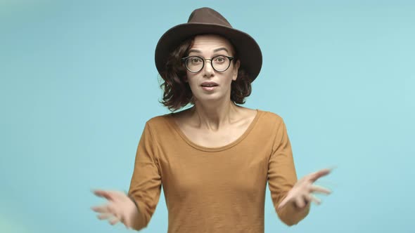 Impressed Young Woman in Glasses and Hipster Hat Shaking Hands in Reaction to Something Big Express
