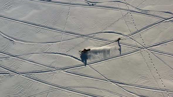 Birdseye Drone Aerial View of Snowmobile and Skier, Winter Snow Fun and Activity on Sunny Day alt