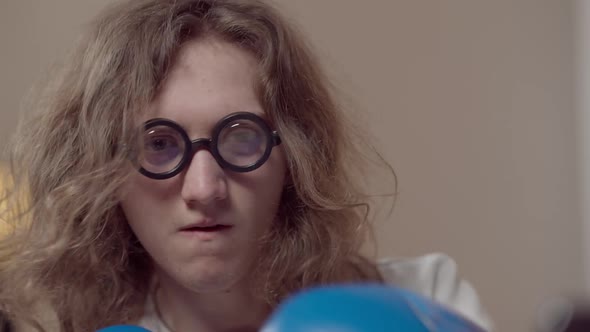 Headshot of Positive Curlyhaired Brunette Man in Nerd Eyeglasses and Boxing Gloves Fighting Camera alt