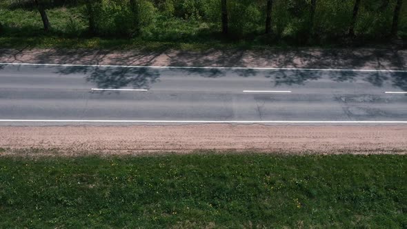 Drone Flies Over the Road Between the Trees and Watching the Cars