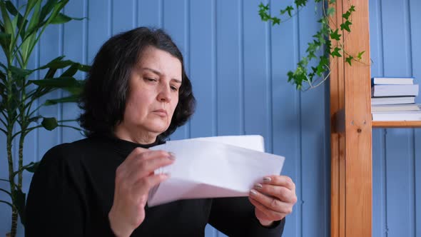 Excited Middle Aged Woman Reading Good News on Letter at Home