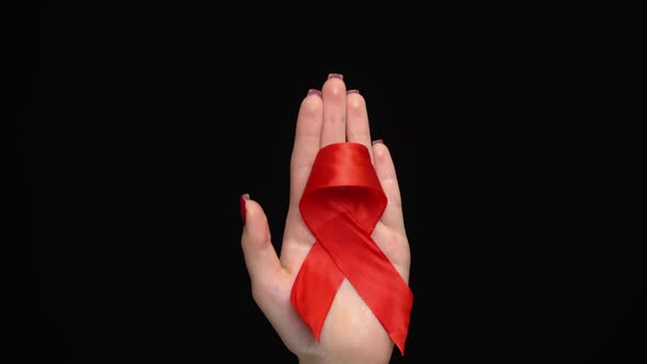 Red Ribbon on Woman's Hand Support for World Aids Day.