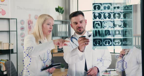 Male and Female Doctors Working Together in Medical Lab and Discussing Patient's X-ray alt