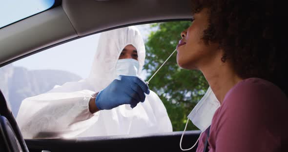 African american woman, having covid test done while sitting in car by medical worker outdoors alt