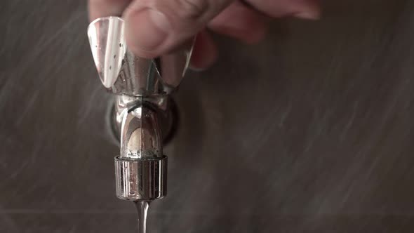 Water Faucet Is Opened By a Man's Hand and Water Flows From It alt