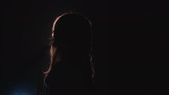 Closeup of the Face of the Singer with Microphone on a Black Smoky Background alt