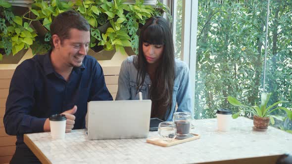 Young couple working on laptop computer in the cafe, man and woman meeting and discussion. alt