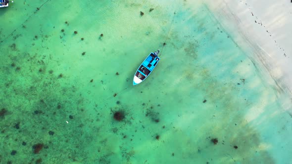 Aerial. Fishing boats floating on perfectly calm crystal clear seawater with corals on the sandy sea alt