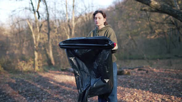 A Young Student Preparing To Collect Garbage in the Woods, Opens a Large Black Garbage Bag