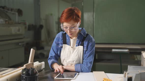 Female Joiner Using Digital Tablet While Working in Carpentry Workshop