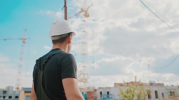 A Builder in a Helmet Is Walking and Inspecting the Construction Site alt