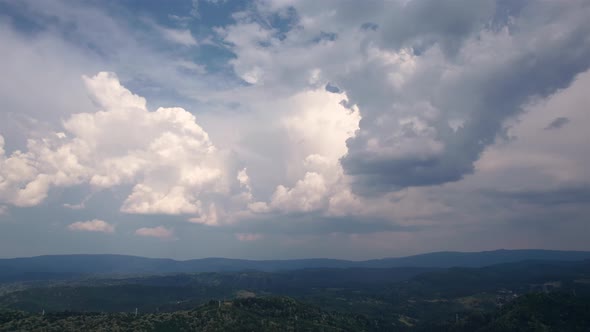 Aerial time lapse of developing storm clouds, over hills
