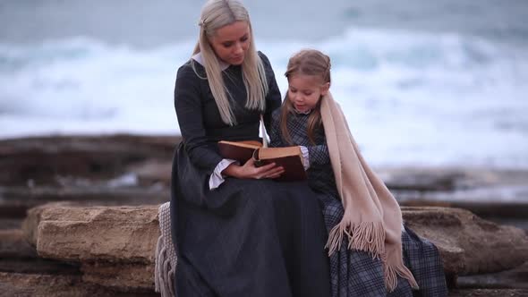 Woman with Girl Reading Book on Seashore Slow Motion Fullhd