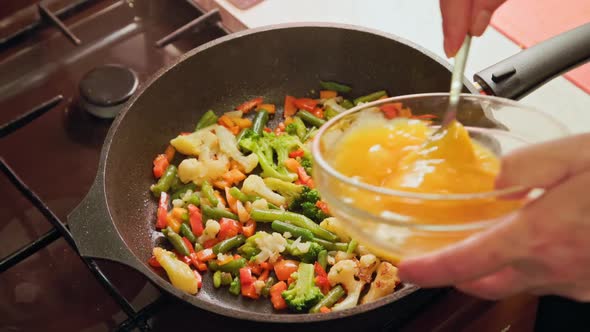 Female Hands Adds a Scrambled Eggs to Fried Vegetables While Cooking Omelette