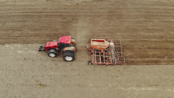 Farmer on a Modern Tractor Performs Processing of Dusty Soil with a Multifunctional Sowing Unit alt