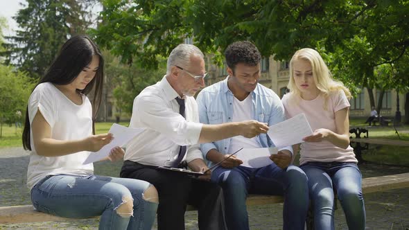 Qualified Teacher Giving Tests to Multiracial Students in Park Near University alt
