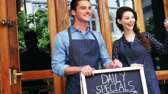 Waiter and waitresses standing with menu board alt