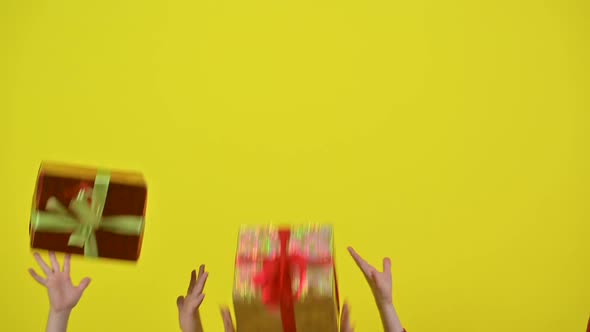 Slow motion of flying gifts on a studio yellow background.