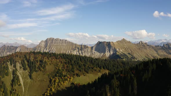 Aerial shot revealing alpine farm (Alpage) nested between to high hills with alpine landscape in the alt